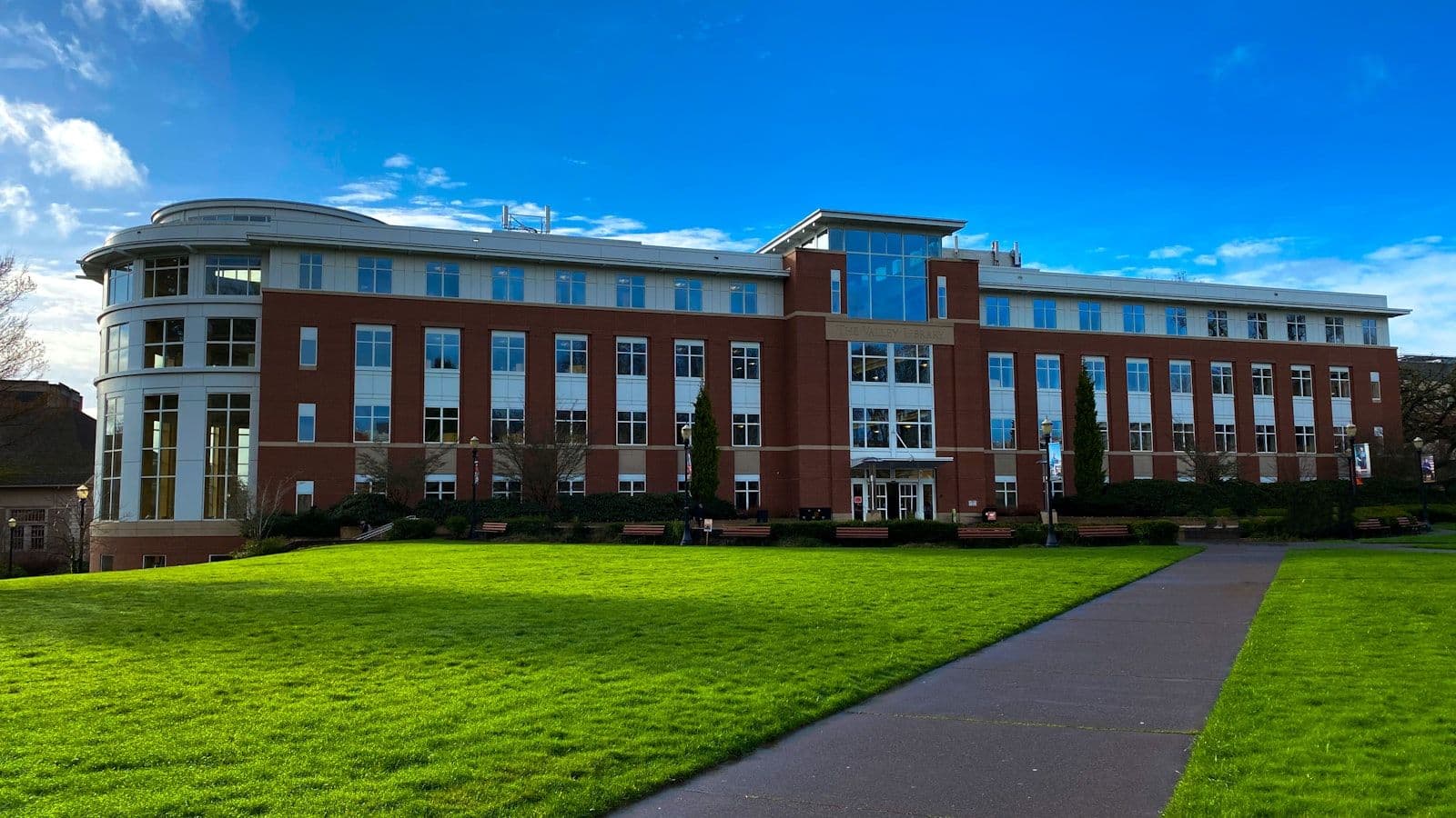 University campus building with green lawn and blue sky